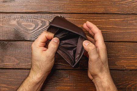 A businessman examines his empty wallet, reflecting on financial difficulties. The scene evokes...