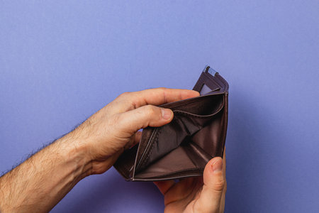 A male businessman examines his empty wallet, feeling the weight of financial challenges. This moment captures the stress and despair tied to budgeting and rising expenses.の写真素材