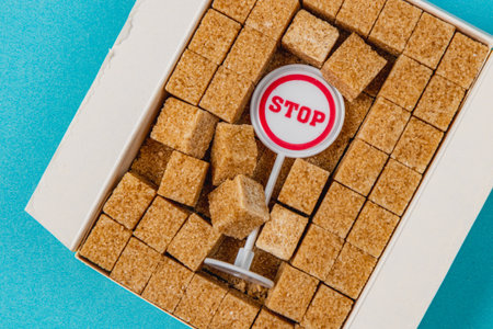 A collection of brown sugar cubes fills a square box, with a playful stop sign icon positioned amid the cubes, all set against a vibrant blue background.の写真素材