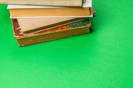 A collection of vintage books is stacked on a bright green surface. The colorful spines and varied textures create an inviting scene that evokes a sense of nostalgia and curiosity.の写真素材