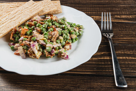 A delicious mix of chopped vegetables and green peas is elegantly plated with crispy flatbread on the side. Enjoying this healthy dish brings a sense of freshness and satisfaction.の写真素材