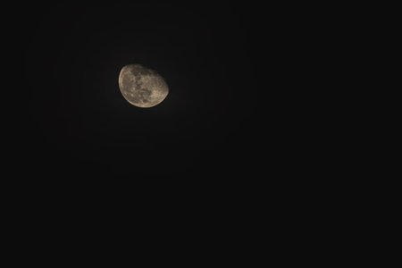 Under a dark sky, the moon glows softly as it hovers among wispy clouds, creating a tranquil atmosphere during the night.の写真素材