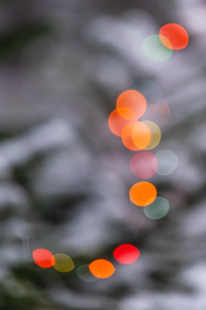 Soft, colorful bokeh lights twinkle against a blurred winter backdrop, evoking warmth and joy.の写真素材