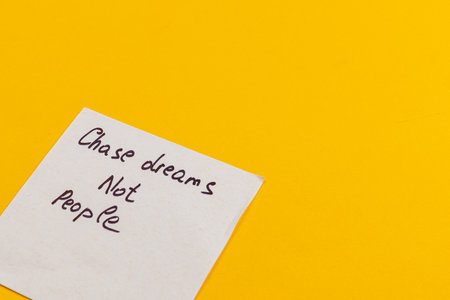 A handwritten note inspires individuals to prioritize their dreams over chasing others. Set against a vibrant yellow backdrop, the message conveys positivity and motivation.の写真素材