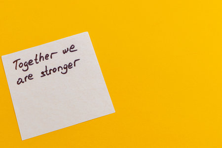 Handwritten note reading together we are stronger contrasts against a vibrant yellow background, symbolizing hope and collaboration, perfect for motivational contexts and teamwork.の写真素材