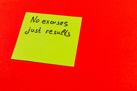 A bright yellow sticky note displays an inspiring phrase urging focus and accountability. This striking note is set against a vivid red backdrop, creating an eye-catching contrast.の写真素材