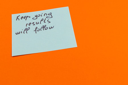 A handwritten note advises to keep going, with the encouraging message that results will follow, placed against a bright orange background for emphasis.の写真素材