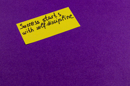 A bright yellow sticky note with the message success starts with self-discipline is placed on a vibrant purple background, providing an inspiring reminder for personal development and motivation.の写真素材