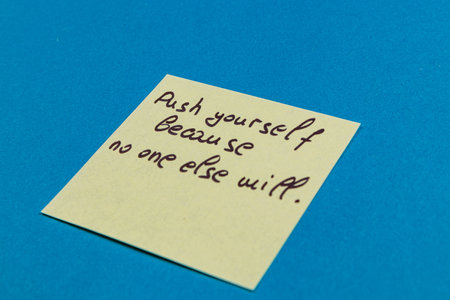 A yellow sticky note rests on a bright blue surface, displaying a motivational message.の写真素材