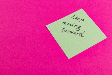 A bright pink background features a green sticky note with the handwritten message to keep moving...