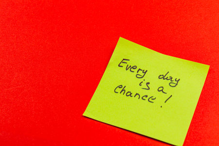 A bright green sticky note features an inspirational message, placed against a striking red background. This captures a moment of encouragement and positivity for daily life.の写真素材