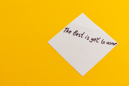 A handwritten note displays the motivational phrase The best is yet to come resting on a vivid yellow surface, radiating positivity and hopefulness.の写真素材