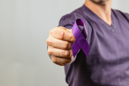 A person displays a purple ribbon, symbolizing awareness for various causes. The individual is dressed in a simple shirt, emphasizing the message of support and advocacy.の写真素材