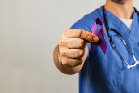 A healthcare professional dressed in scrubs holds a purple awareness ribbon, symbolizing support for various causes. The focus is on their commitment to advocacy and health awareness.の写真素材