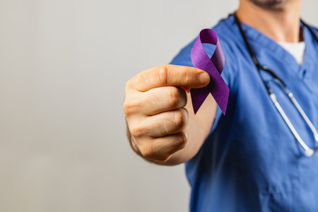 A healthcare professional in blue scrubs is holding a purple ribbon with a stethoscope around their neck. The ribbon represents awareness for health issues, emphasizing support and advocacy.の写真素材