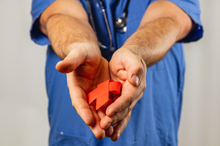 A healthcare professional in scrubs offers a bright red healthcare symbol with both hands,...