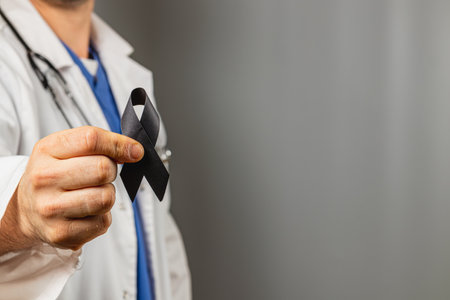A healthcare professional wearing a white coat and stethoscope holds a black ribbon, symbolizing remembrance or support. The setting is neutral, emphasizing the message of solidarity.の写真素材