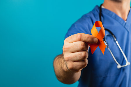 A healthcare worker in scrubs displays an orange ribbon, symbolizing support for an awareness campaign. The background is a vibrant blue, emphasizing the message of unity and hope.の写真素材