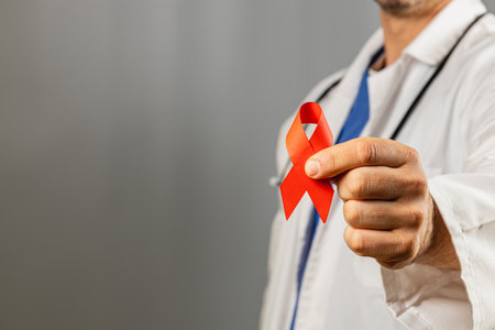 A health professional holds a red ribbon, symbolizing support for HIV awareness. The figure is dressed in a white coat, promoting healthcare and community education.の写真素材