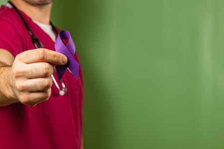A healthcare professional holds a purple ribbon in front of a green background, symbolizing awareness for various health issues. This gesture promotes education and support for the community.の写真素材