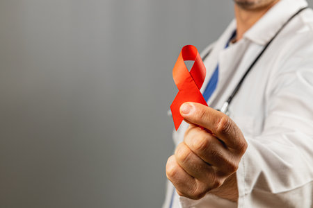 A healthcare professional displays a red ribbon emphasizing the importance of HIV awareness and education. The focus highlights the symbol's significance in promoting health initiatives.の写真素材