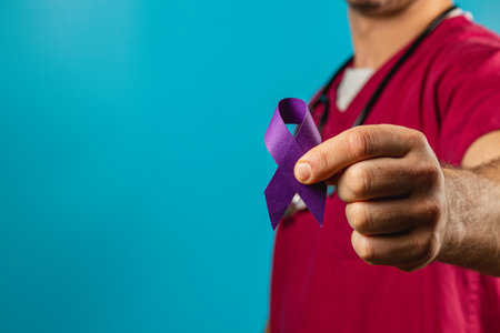 A health worker holds a purple awareness ribbon, symbolizing support for various causes, in front of a vibrant blue backdrop. This gesture highlights the importance of advocacy and education.の写真素材