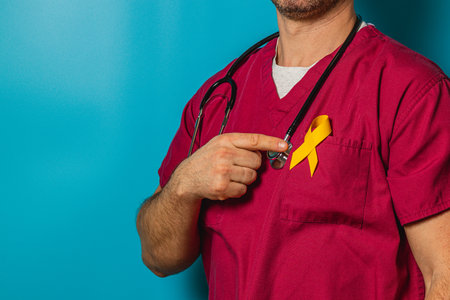 A healthcare worker in red scrubs points to a yellow ribbon pinned to their chest. This symbolizes support and awareness for a specific cause, promoting health advocacy.の写真素材
