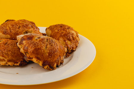 A plate holds several golden-brown pastries with a crispy exterior, set against a bright yellow background. The pastries look delicious and ready to enjoy.の写真素材
