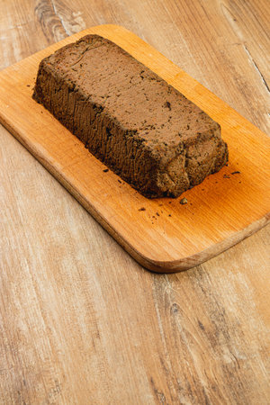 A freshly made block of chicken liver pate rests on a sturdy wooden cutting board, showcasing a rich, smooth texture. This savory delicacy is perfect for spreading on crackers or bread.の写真素材