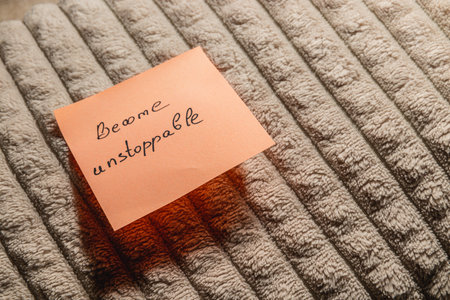 A handwritten note with the phrase Become unstoppable rests on a soft, textured surface. The note promotes motivation and determination during personal reflection or goal setting.の写真素材
