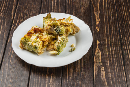 Savory casserole features layers of tender chicken fillet, sautÃ©ed broccoli, and creamy sour cream with garlic, presented on a rustic wooden table for a comforting meal.の写真素材