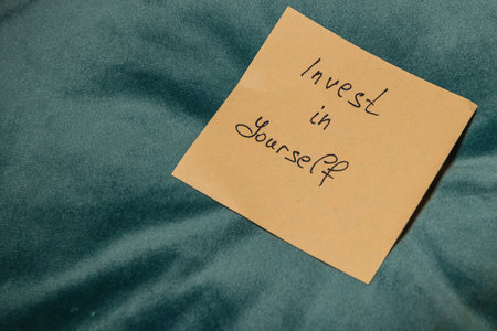 A motivational note saying Invest in yourself is placed on a soft teal fabric surface, emphasizing self-improvement and personal growth.の写真素材