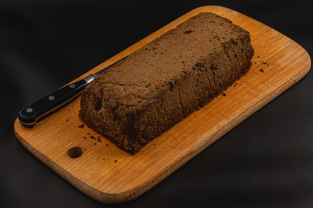 A fresh loaf of homemade chicken liver pate sits on a wooden cutting board, accompanied by a knife. The pate has a rich, smooth texture and is ready to be served as a delicious appetizer.の写真素材