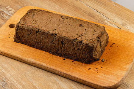 A block of homemade chicken liver pate sits on a wooden cutting board, showcasing its rich color and texture. This delicacy is perfect for spreading on crusty bread at gatherings.の写真素材