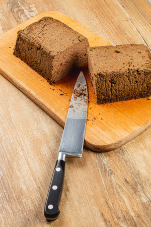 Freshly made chicken liver pate is neatly sliced on a wooden cutting board, accompanied by a sharp knife. This delicacy is perfect for serving at gatherings or special occasions.の写真素材