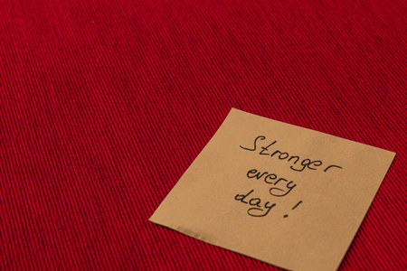 A handwritten note placed on a deep red surface expresses a motivational message. The phrase urges...