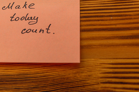 A handwritten note on a pink sticky pad reads a motivational message urging people to make today...