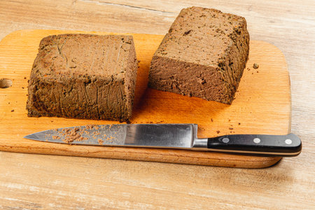 Two blocks of rich, homemade chicken liver pate are displayed on a rustic wooden board alongside a sharp knife, perfect for spreading on toasted bread or crackers.の写真素材