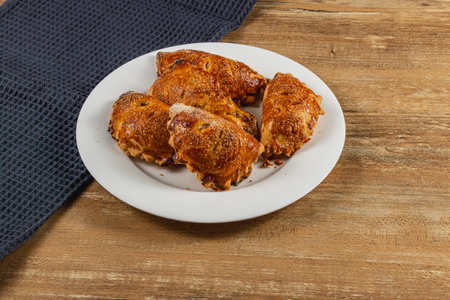 Freshly baked pumpkin pastries displayed on a white plate. Their golden-brown crusts are adorned with a sprinkle of spices. A dark cloth complements the rustic wooden background.の写真素材