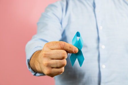 A man holds a blue ribbon, serving as a powerful symbol of awareness for prostate cancer. This gesture promotes health education and prevention efforts in men's health.の写真素材