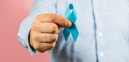 A person holds a blue ribbon, a symbol representing awareness for men's health issues and cancer prevention. This act promotes education and support for various health challenges.の写真素材