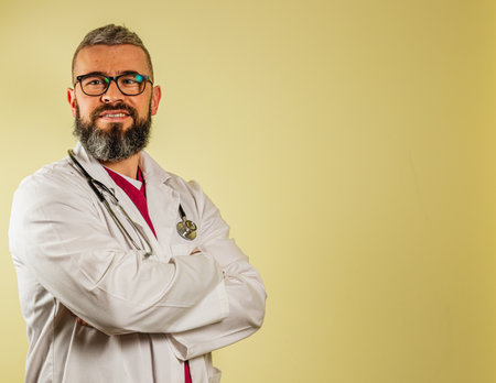 A male healthcare worker stands with arms crossed, smiling confidently in a clinic.の写真素材