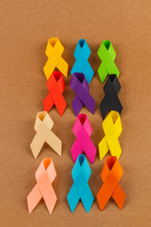 A collection of colorful ribbons laid out on a brown background symbolizes different cancer awareness campaigns. Each ribbon color represents a unique cause, promoting support and prevention.の写真素材