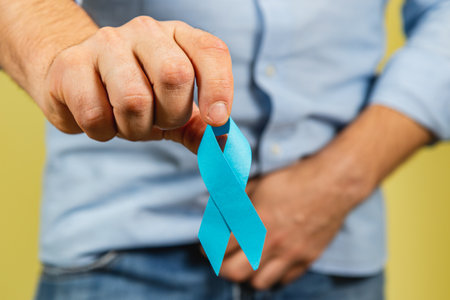 A man holds a blue ribbon to promote awareness for prostate cancer. This act symbolizes support for those affected by this disease and emphasizes the importance of health education and prevention.の写真素材