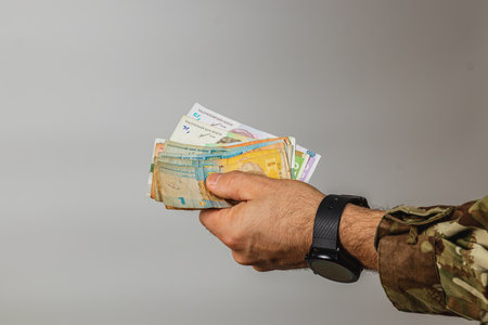 A person is holding a bundle of different banknotes in their hand, showcasing the variety of currencies with a plain background that emphasizes the money.の写真素材