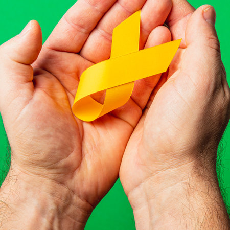 Two hands gently cradle a yellow ribbon, symbolizing support and awareness for cancer. This representation conveys a message of solidarity and hope for those affected.の写真素材