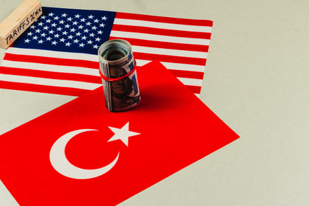 Displays two flags, one of the USA and one of Turkey, with a rolled stack of money suggesting trade negotiations, tariffs, and financial dealings.の写真素材