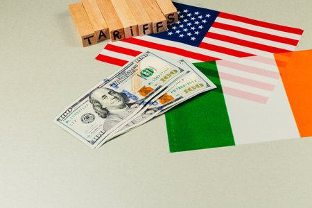 Currency and flags of USA and Italy illustrate trade discussions on tariffs. The wooden block spells tariffs, highlighting current political and economic discourse.の写真素材