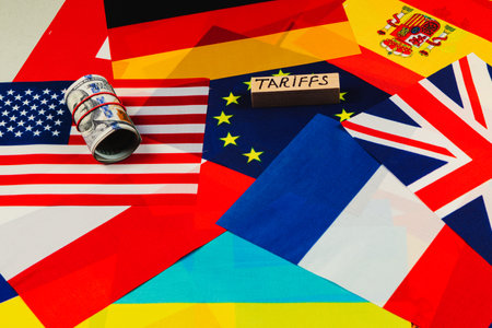 Flags representing various countries are displayed along with a roll of cash and a block labeled tariffs. This setup illustrates the complexities of international trade relations.の写真素材