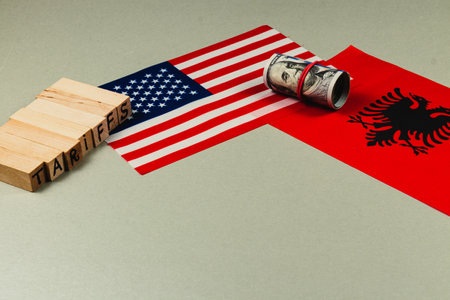 Blocks spelling tariffs are placed alongside US and Albania flags, symbolizing the complex political and economic negotiations surrounding trade.の写真素材